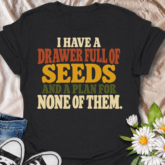 A funny gardening T-shirt for anyone who has collected far more seeds than they have actual planting plans. The phrase “I Have a Drawer Full of Seeds and a Plan for None of Them” captures the wonderfully chaotic side of gardening with dry, relatable humor. Its bold retro typography makes the joke easy to read while keeping the design clean and wearable. It makes a great gift for seed savers, vegetable gardeners, flower growers, and anyone who cannot resist another packet at the garden center. Ideal for gard