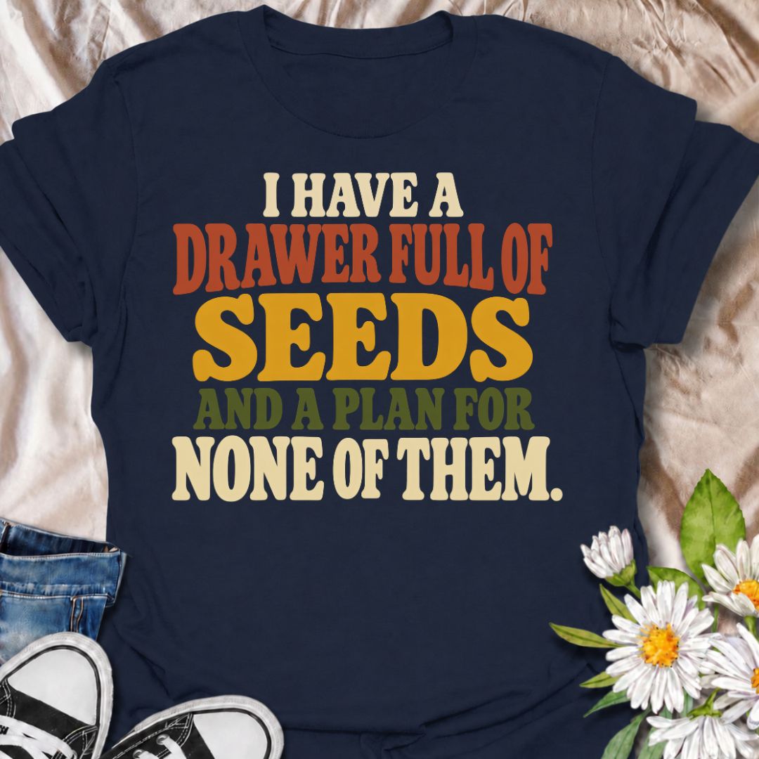 A funny gardening T-shirt for anyone who has collected far more seeds than they have actual planting plans. The phrase “I Have a Drawer Full of Seeds and a Plan for None of Them” captures the wonderfully chaotic side of gardening with dry, relatable humor. Its bold retro typography makes the joke easy to read while keeping the design clean and wearable. It makes a great gift for seed savers, vegetable gardeners, flower growers, and anyone who cannot resist another packet at the garden center. Ideal for gard