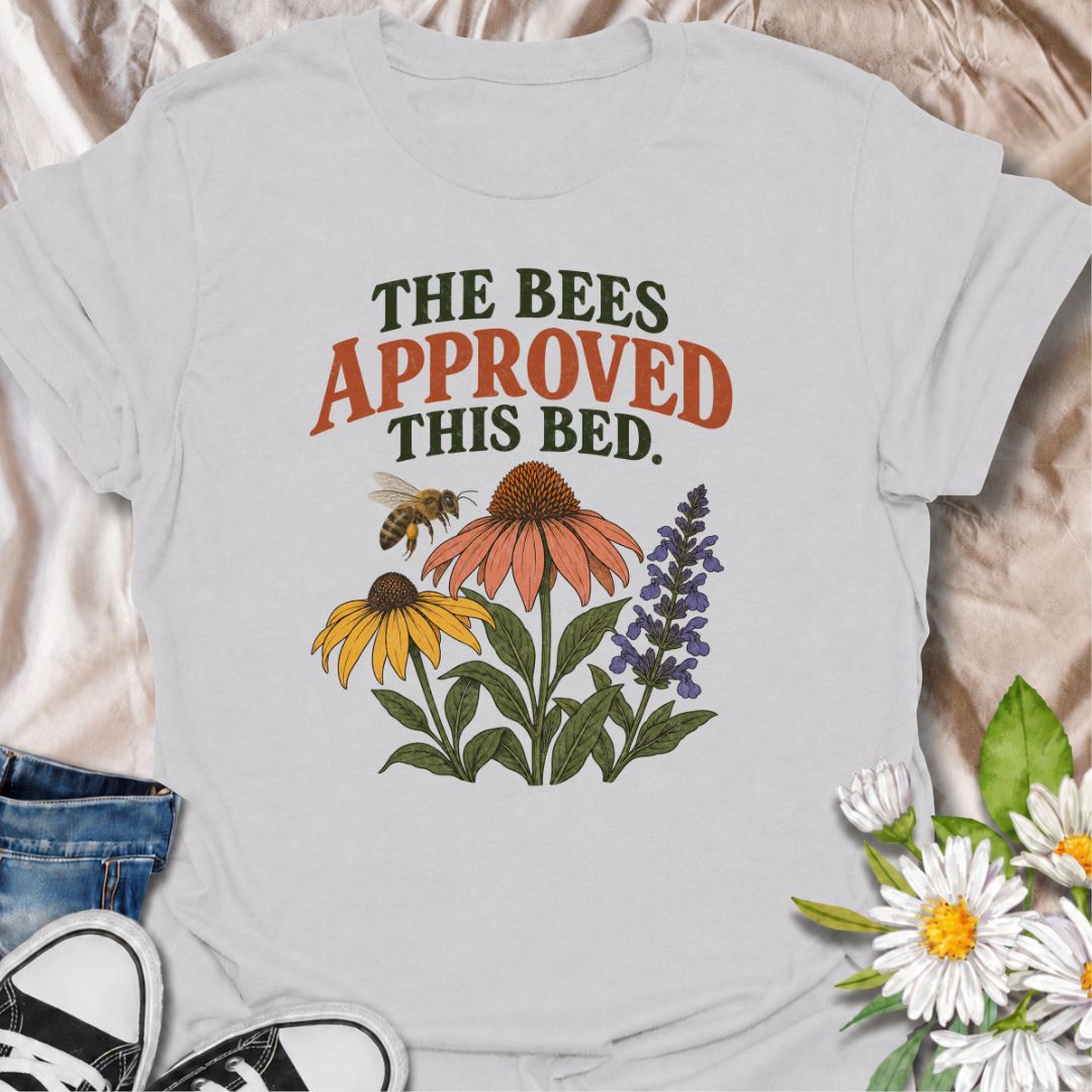 A cheerful gardening T-shirt for anyone who takes pride in growing flowers the pollinators love. The phrase “The Bees Approved This Bed” pairs perfectly with coneflowers, black-eyed Susans, salvia, and a visiting bee for a garden design with real pollinator appeal. It is ideal for flower gardeners, wildlife gardeners, native plant lovers, and anyone creating a bee-friendly backyard. The design makes a lovely gift for gardeners who enjoy supporting bees while filling their beds with color. Perfect for garden