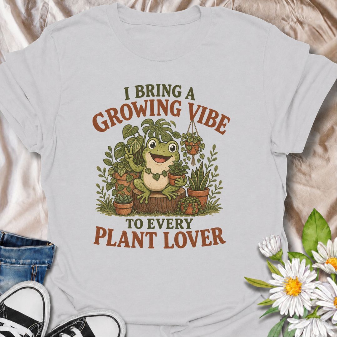 A playful plant T-shirt for anyone who brings cheerful energy wherever the houseplants are. Featuring a happy frog surrounded by lush potted plants, the phrase “I Bring a Growing Vibe to Every Plant Lover” gives the design a fun, lighthearted botanical feel. It is perfect for plant parents, houseplant collectors, indoor gardeners, and frog lovers alike. The colorful character-led artwork makes it a great gift for anyone building their own indoor jungle. Ideal for nursery trips, plant swaps, greenhouse days,