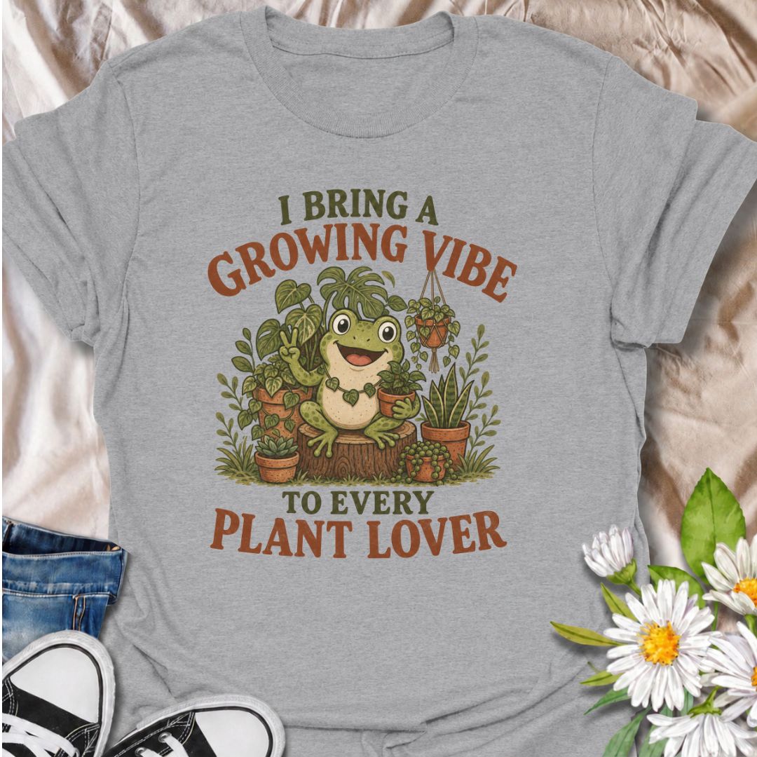 A playful plant T-shirt for anyone who brings cheerful energy wherever the houseplants are. Featuring a happy frog surrounded by lush potted plants, the phrase “I Bring a Growing Vibe to Every Plant Lover” gives the design a fun, lighthearted botanical feel. It is perfect for plant parents, houseplant collectors, indoor gardeners, and frog lovers alike. The colorful character-led artwork makes it a great gift for anyone building their own indoor jungle. Ideal for nursery trips, plant swaps, greenhouse days,