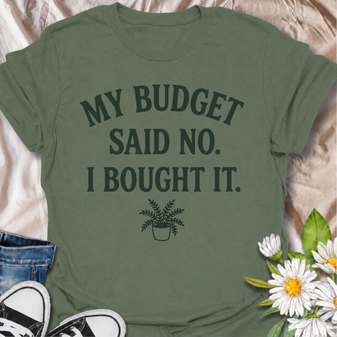 A funny plant T-shirt for anyone who knows a sensible budget can disappear the moment a new plant comes into view. The phrase “My Budget Said No. I Bought It.” captures the reality of impulsive plant shopping with simple, relatable humor. Featuring a small potted plant beneath bold retro typography, the design stays clean, readable, and easy to wear. It makes a great gift for plant parents, houseplant collectors, and nursery regulars who can never resist one more purchase. Perfect for plant swaps, garden ce