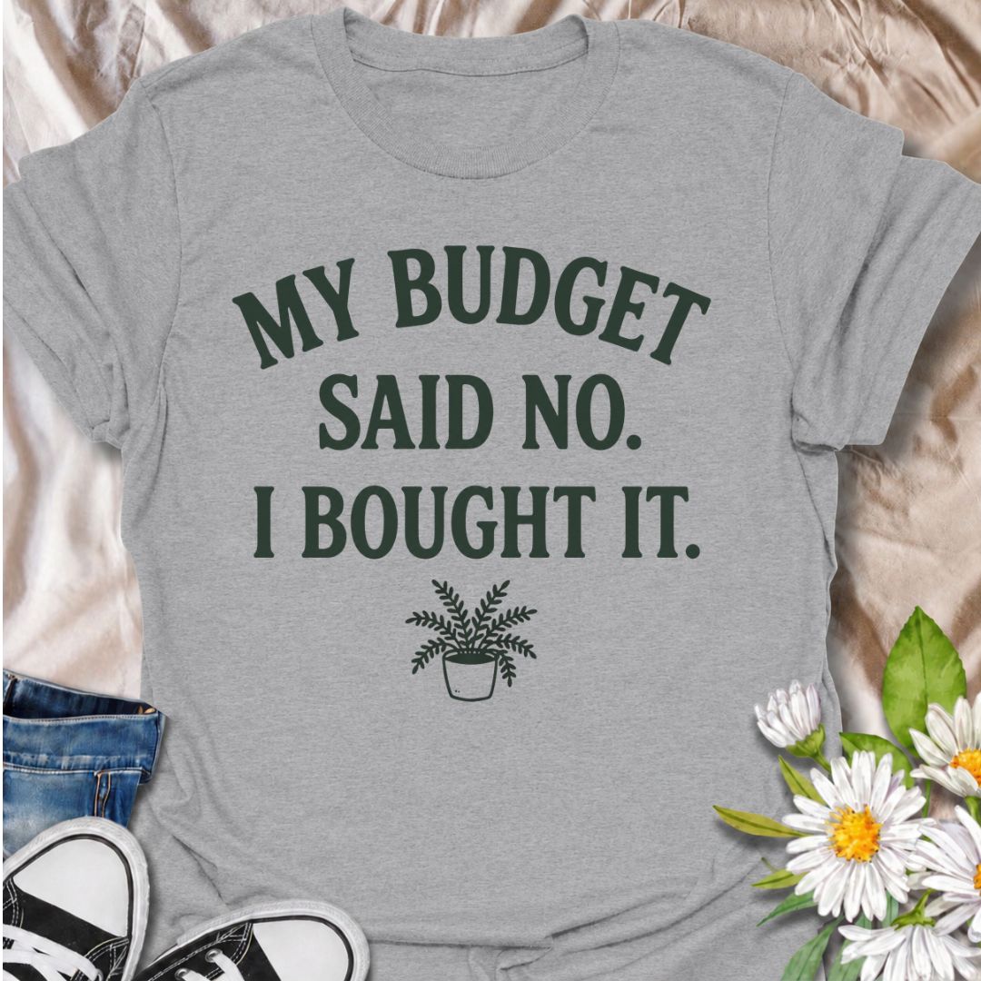 A funny plant T-shirt for anyone who knows a sensible budget can disappear the moment a new plant comes into view. The phrase “My Budget Said No. I Bought It.” captures the reality of impulsive plant shopping with simple, relatable humor. Featuring a small potted plant beneath bold retro typography, the design stays clean, readable, and easy to wear. It makes a great gift for plant parents, houseplant collectors, and nursery regulars who can never resist one more purchase. Perfect for plant swaps, garden ce