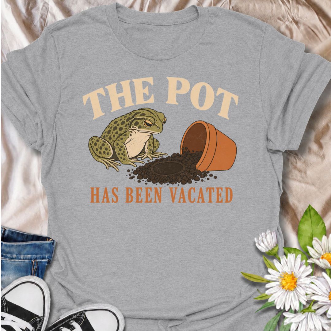 A funny plant T-shirt for anyone who knows an empty pot never stays empty for long. Featuring a deadpan frog beside an overturned planter and a suspiciously vacant patch of soil, this design gives “The Pot Has Been Vacated” a dry, slightly absurd sense of humor. It is perfect for houseplant lovers, plant parents, gardeners, and anyone who treats an empty pot as an invitation to buy something new. The vintage-style illustration makes it feel distinctive while still being easy to wear. A fun gift for plant co