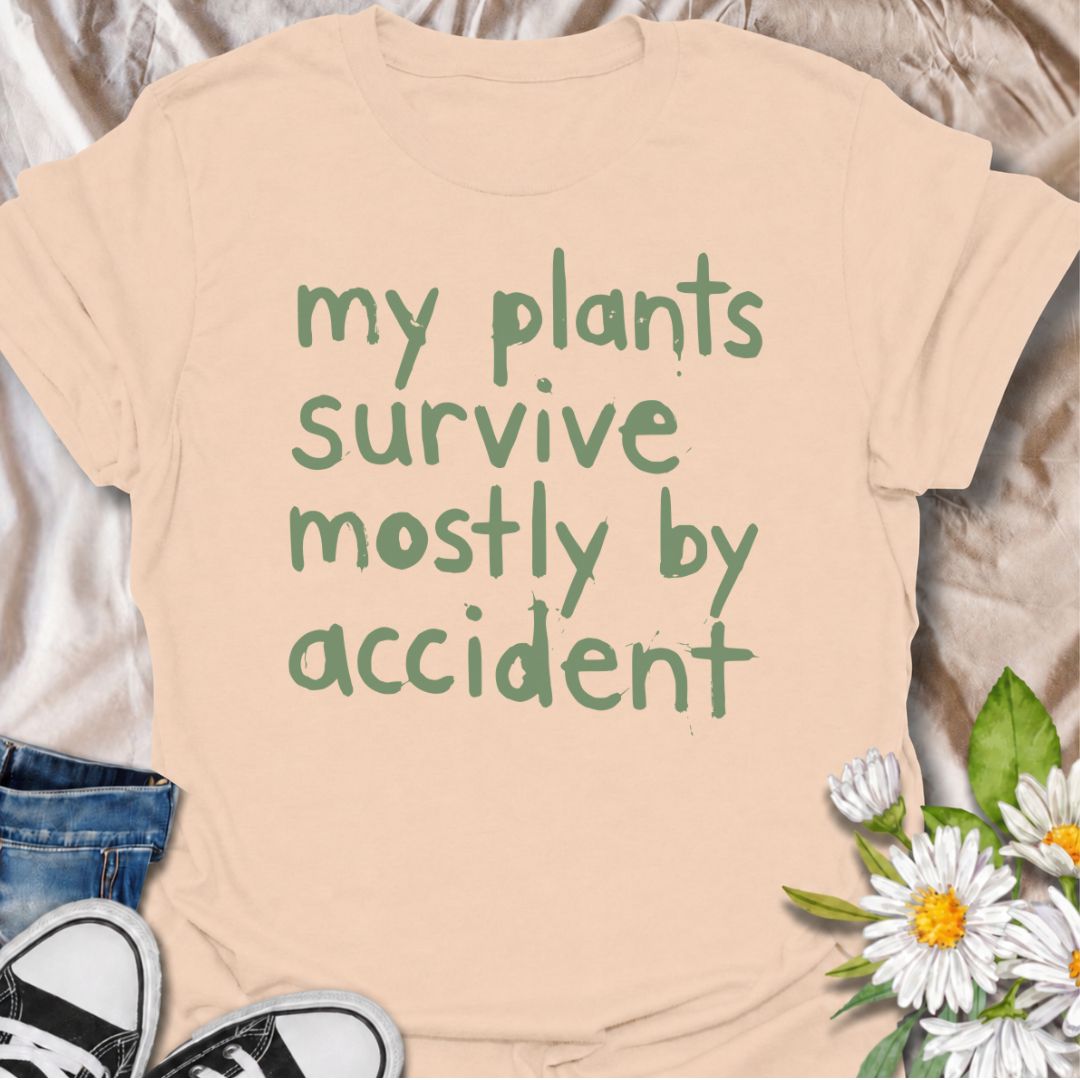 A funny plant T-shirt for anyone whose houseplants are doing surprisingly well despite a slightly questionable care routine. The phrase “My Plants Survive Mostly by Accident” delivers dry, self-deprecating humor that plant parents and indoor gardeners will instantly relate to. Its simple hand-drawn typography keeps the design casual, modern, and easy to wear. It makes a great gift for houseplant lovers, accidental green thumbs, and anyone who is still figuring out what their plants actually need. Perfect fo
