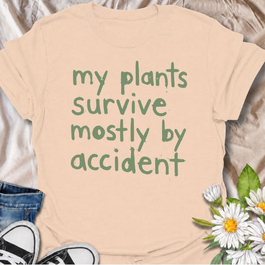 A funny plant T-shirt for anyone whose houseplants are doing surprisingly well despite a slightly questionable care routine. The phrase “My Plants Survive Mostly by Accident” delivers dry, self-deprecating humor that plant parents and indoor gardeners will instantly relate to. Its simple hand-drawn typography keeps the design casual, modern, and easy to wear. It makes a great gift for houseplant lovers, accidental green thumbs, and anyone who is still figuring out what their plants actually need. Perfect fo