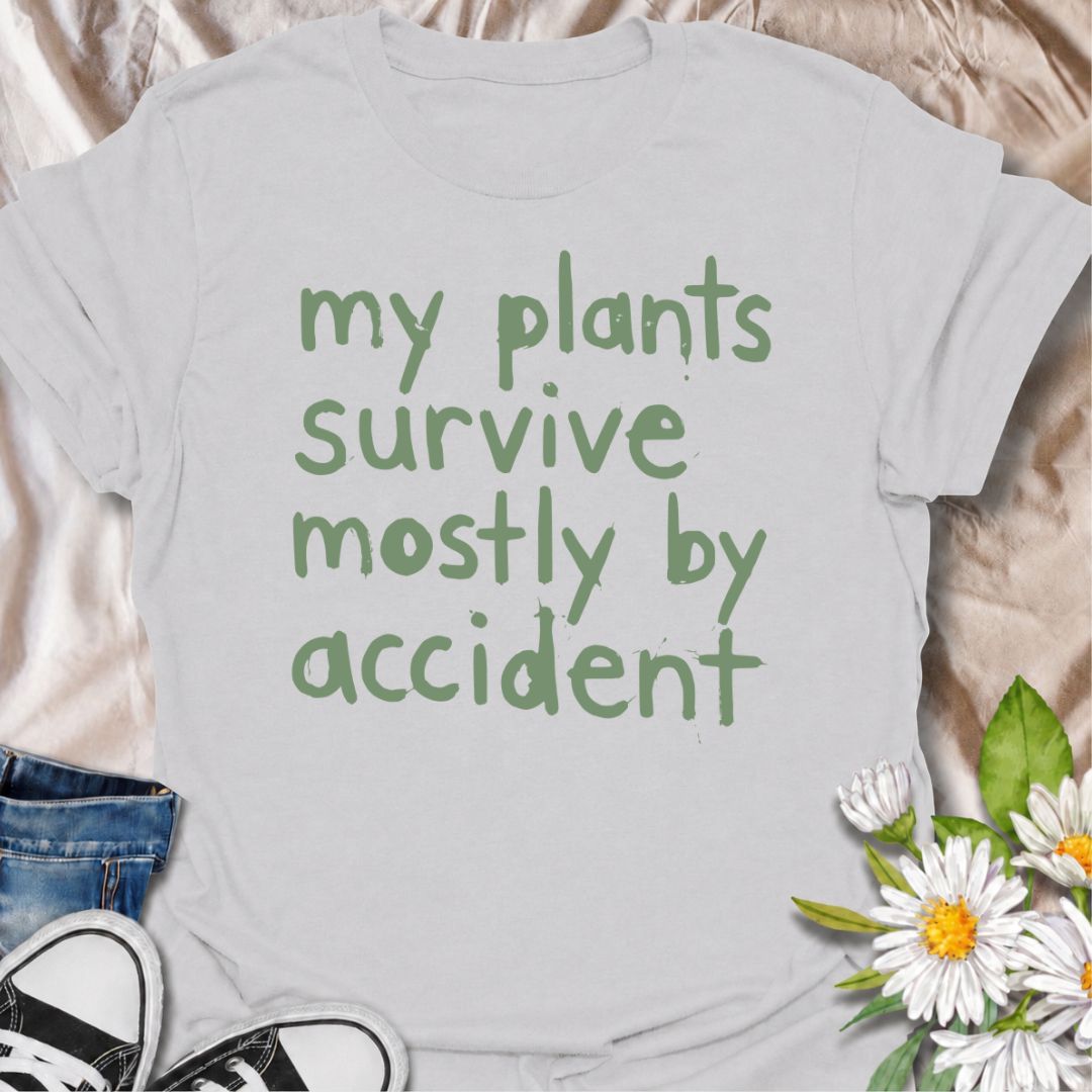 A funny plant T-shirt for anyone whose houseplants are doing surprisingly well despite a slightly questionable care routine. The phrase “My Plants Survive Mostly by Accident” delivers dry, self-deprecating humor that plant parents and indoor gardeners will instantly relate to. Its simple hand-drawn typography keeps the design casual, modern, and easy to wear. It makes a great gift for houseplant lovers, accidental green thumbs, and anyone who is still figuring out what their plants actually need. Perfect fo