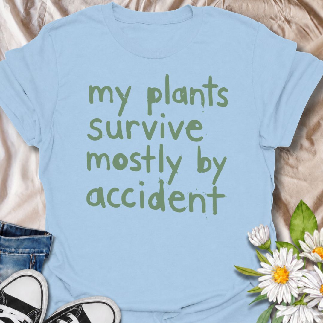A funny plant T-shirt for anyone whose houseplants are doing surprisingly well despite a slightly questionable care routine. The phrase “My Plants Survive Mostly by Accident” delivers dry, self-deprecating humor that plant parents and indoor gardeners will instantly relate to. Its simple hand-drawn typography keeps the design casual, modern, and easy to wear. It makes a great gift for houseplant lovers, accidental green thumbs, and anyone who is still figuring out what their plants actually need. Perfect fo