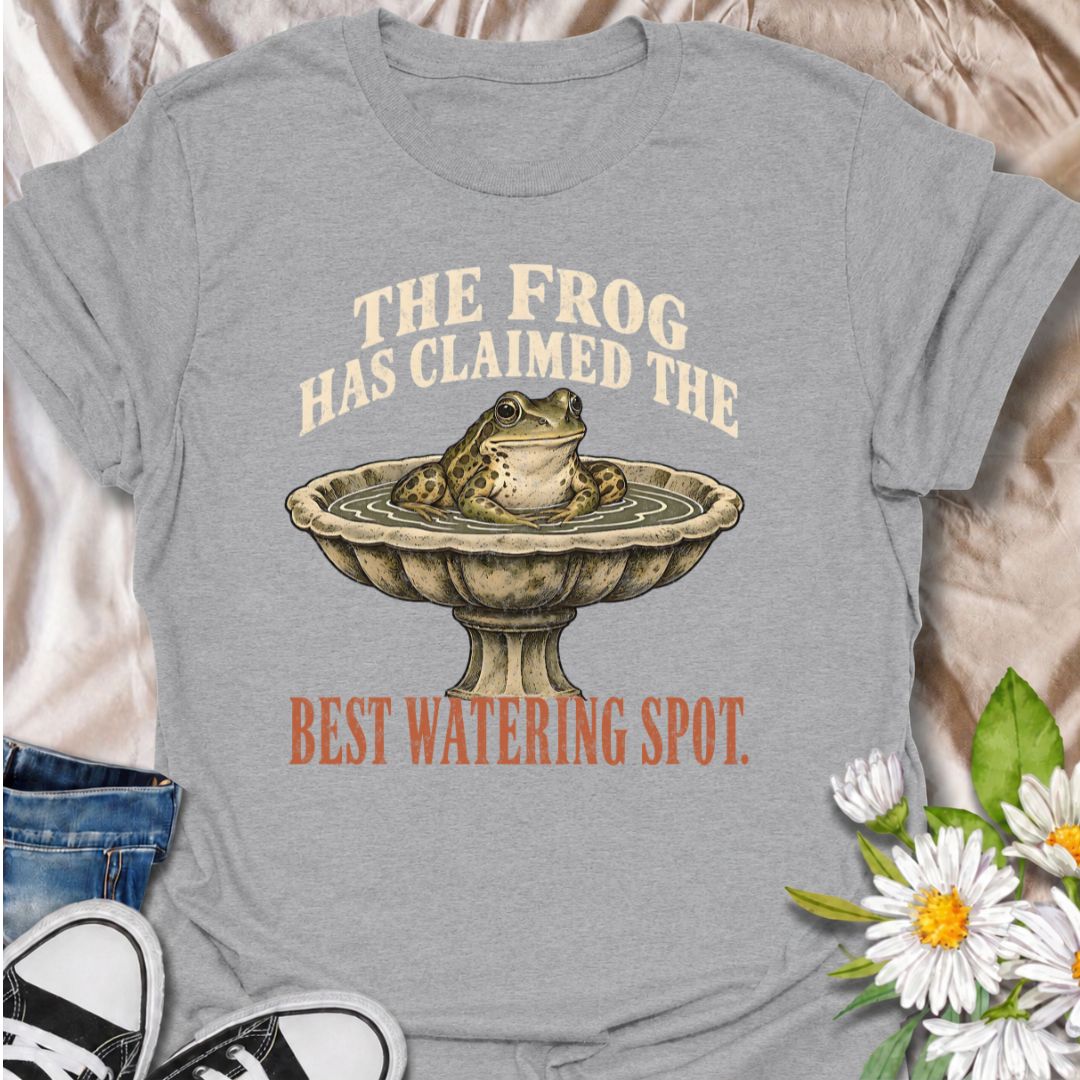 A funny gardening T-shirt for anyone whose garden wildlife has decided certain spots now belong to them. The phrase “The Frog Has Claimed the Best Watering Spot” pairs perfectly with a content-looking frog sitting in a birdbath for dry, relatable garden humor. It is ideal for backyard gardeners, wildlife gardeners, frog lovers, and anyone who enjoys seeing unexpected visitors around the garden. The vintage-style illustration gives the design personality while keeping it easy to wear. A great gift for garden