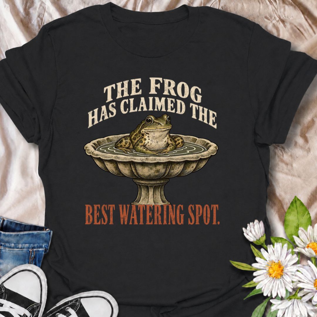 A funny gardening T-shirt for anyone whose garden wildlife has decided certain spots now belong to them. The phrase “The Frog Has Claimed the Best Watering Spot” pairs perfectly with a content-looking frog sitting in a birdbath for dry, relatable garden humor. It is ideal for backyard gardeners, wildlife gardeners, frog lovers, and anyone who enjoys seeing unexpected visitors around the garden. The vintage-style illustration gives the design personality while keeping it easy to wear. A great gift for garden