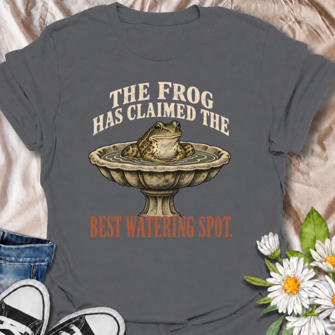 A funny gardening T-shirt for anyone whose garden wildlife has decided certain spots now belong to them. The phrase “The Frog Has Claimed the Best Watering Spot” pairs perfectly with a content-looking frog sitting in a birdbath for dry, relatable garden humor. It is ideal for backyard gardeners, wildlife gardeners, frog lovers, and anyone who enjoys seeing unexpected visitors around the garden. The vintage-style illustration gives the design personality while keeping it easy to wear. A great gift for garden
