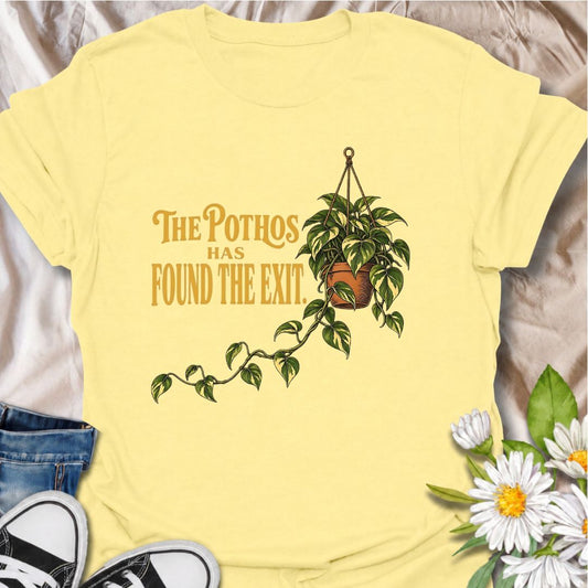 A funny houseplant T-shirt for anyone whose pothos has stopped respecting the limits of the pot. The phrase “The Pothos Found the Exit” captures that familiar moment when a trailing vine starts heading across the room on its own mission. Featuring a hanging pothos with a long wandering stem, this design is perfect for plant parents, houseplant collectors, and indoor gardeners. It makes a great gift for pothos lovers and anyone whose indoor jungle is slowly taking over the house. Ideal for nursery trips, pla