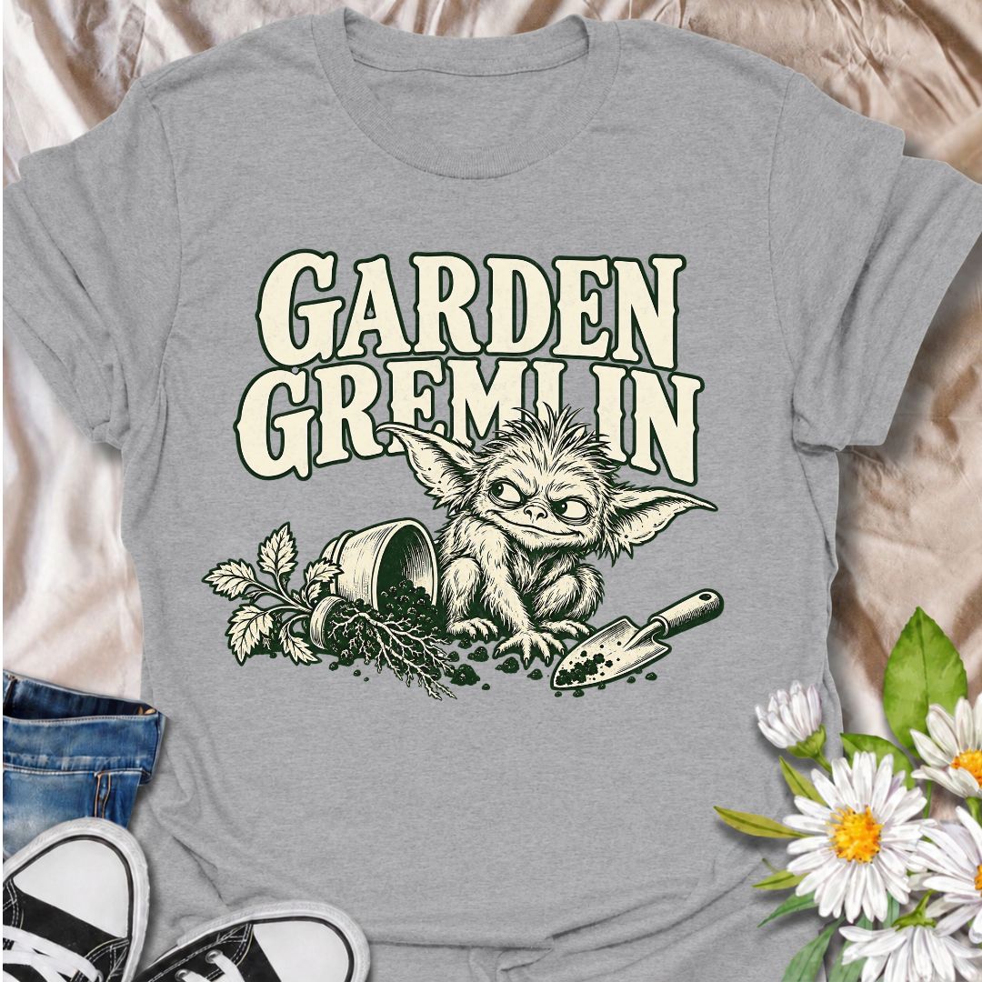 A funny gardening T-shirt for anyone who turns a simple garden job into a slightly chaotic adventure. Featuring a mischievous little garden gremlin beside spilled soil, a tipped plant pot, and a hand trowel, this design is packed with personality and relatable garden humor. The bold “Garden Gremlin” phrase makes it perfect for backyard gardeners, plant lovers, and anyone who is rarely clean or organized once gardening starts. It makes a fun gift for gardeners who embrace the mess, the dirt, and the occasion