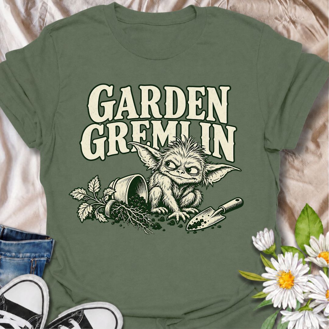 A funny gardening T-shirt for anyone who turns a simple garden job into a slightly chaotic adventure. Featuring a mischievous little garden gremlin beside spilled soil, a tipped plant pot, and a hand trowel, this design is packed with personality and relatable garden humor. The bold “Garden Gremlin” phrase makes it perfect for backyard gardeners, plant lovers, and anyone who is rarely clean or organized once gardening starts. It makes a fun gift for gardeners who embrace the mess, the dirt, and the occasion