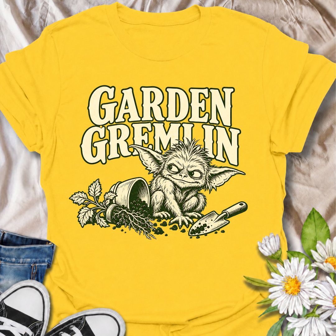 A funny gardening T-shirt for anyone who turns a simple garden job into a slightly chaotic adventure. Featuring a mischievous little garden gremlin beside spilled soil, a tipped plant pot, and a hand trowel, this design is packed with personality and relatable garden humor. The bold “Garden Gremlin” phrase makes it perfect for backyard gardeners, plant lovers, and anyone who is rarely clean or organized once gardening starts. It makes a fun gift for gardeners who embrace the mess, the dirt, and the occasion