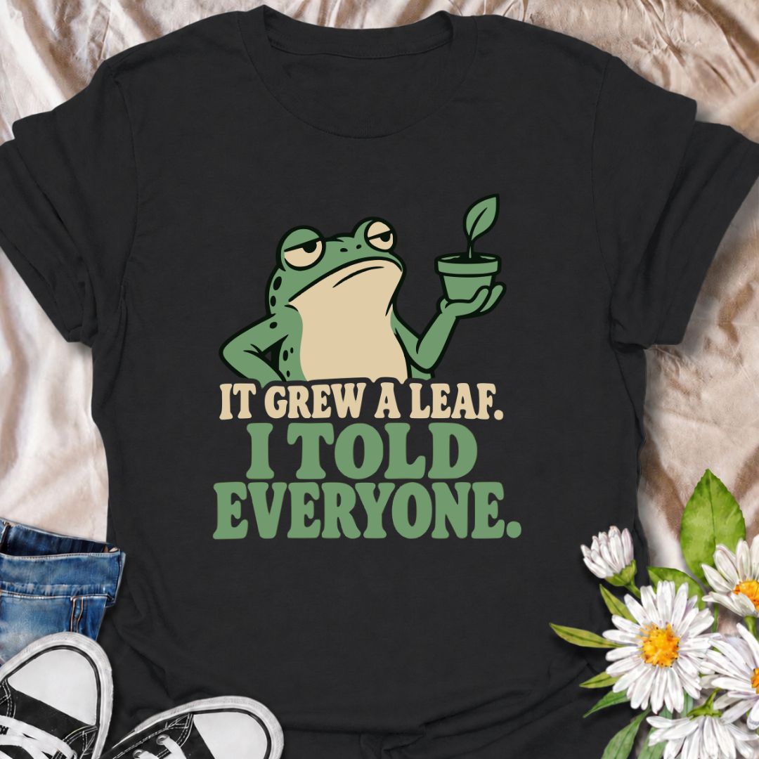 A funny plant T-shirt for anyone who celebrates every tiny bit of new growth like a major event. Featuring a deadpan frog proudly holding up a small plant, the phrase “It Grew a Leaf. I Told Everyone.” captures classic plant-parent behavior perfectly. It is ideal for houseplant lovers, indoor gardeners, propagation fans, and anyone who checks their plants for new growth far too often. The character-led design keeps the humor clear while giving it plenty of personality. A great gift for plant collectors, fro