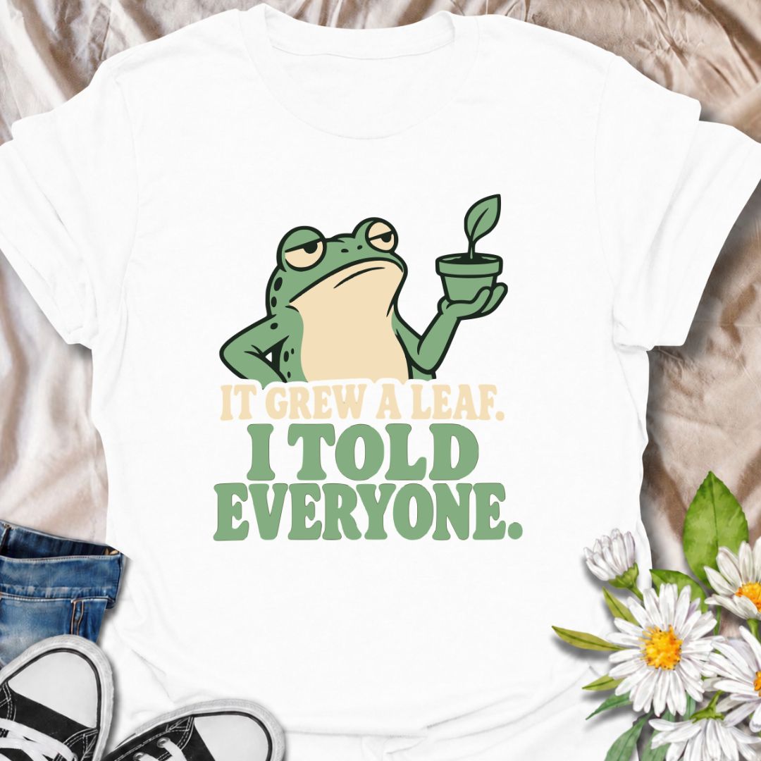 A funny plant T-shirt for anyone who celebrates every tiny bit of new growth like a major event. Featuring a deadpan frog proudly holding up a small plant, the phrase “It Grew a Leaf. I Told Everyone.” captures classic plant-parent behavior perfectly. It is ideal for houseplant lovers, indoor gardeners, propagation fans, and anyone who checks their plants for new growth far too often. The character-led design keeps the humor clear while giving it plenty of personality. A great gift for plant collectors, fro