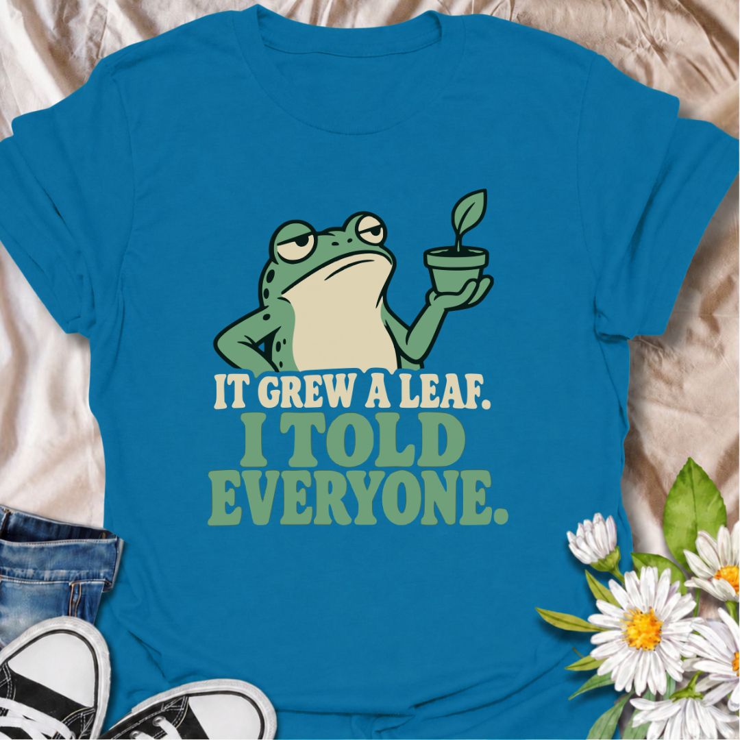 A funny plant T-shirt for anyone who celebrates every tiny bit of new growth like a major event. Featuring a deadpan frog proudly holding up a small plant, the phrase “It Grew a Leaf. I Told Everyone.” captures classic plant-parent behavior perfectly. It is ideal for houseplant lovers, indoor gardeners, propagation fans, and anyone who checks their plants for new growth far too often. The character-led design keeps the humor clear while giving it plenty of personality. A great gift for plant collectors, fro