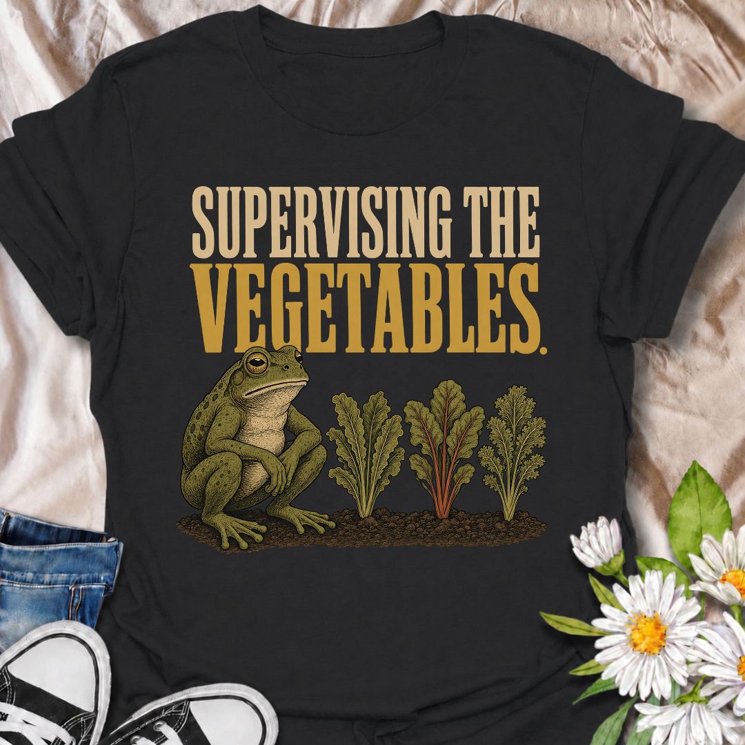 A funny gardening T-shirt for anyone who spends nearly as much time watching the vegetable patch as working in it. Featuring a deadpan frog keeping a close eye on a neat row of leafy greens, the phrase “Supervising the Vegetables” delivers dry, character-led garden humor. It is perfect for vegetable gardeners, backyard growers, allotment lovers, and anyone who checks on their crops several times a day. The vintage-style illustration gives the design plenty of personality while still keeping it easy to wear.