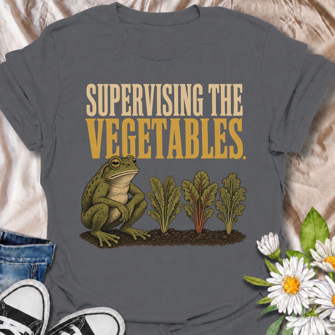 A funny gardening T-shirt for anyone who spends nearly as much time watching the vegetable patch as working in it. Featuring a deadpan frog keeping a close eye on a neat row of leafy greens, the phrase “Supervising the Vegetables” delivers dry, character-led garden humor. It is perfect for vegetable gardeners, backyard growers, allotment lovers, and anyone who checks on their crops several times a day. The vintage-style illustration gives the design plenty of personality while still keeping it easy to wear.