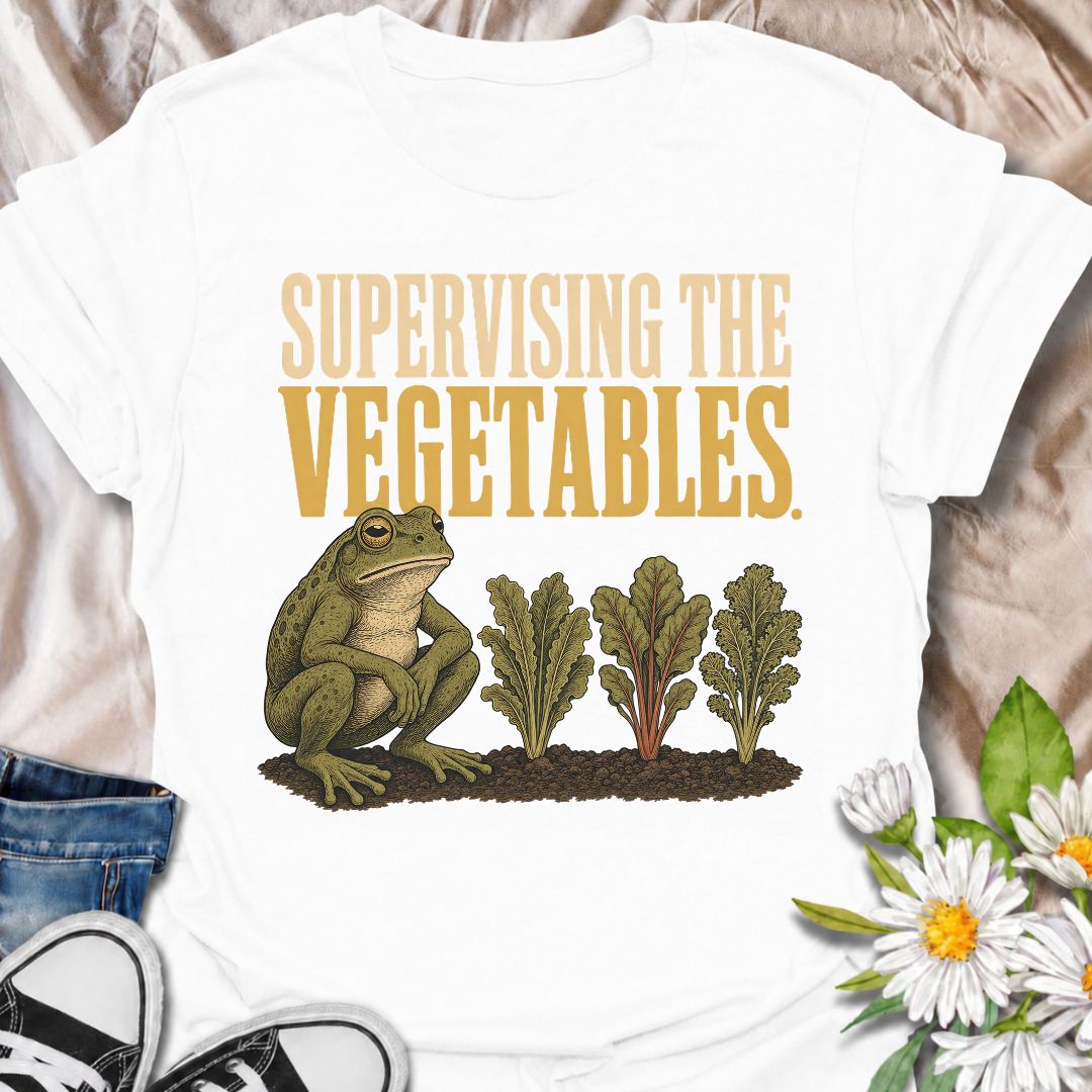 A funny gardening T-shirt for anyone who spends nearly as much time watching the vegetable patch as working in it. Featuring a deadpan frog keeping a close eye on a neat row of leafy greens, the phrase “Supervising the Vegetables” delivers dry, character-led garden humor. It is perfect for vegetable gardeners, backyard growers, allotment lovers, and anyone who checks on their crops several times a day. The vintage-style illustration gives the design plenty of personality while still keeping it easy to wear.