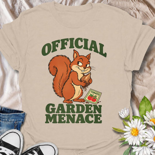 A funny gardening T-shirt for anyone who knows the local squirrels are never innocent. Featuring a smug squirrel clutching a stolen bulb beside a packet of tomato seeds, the phrase “Official Garden Menace” captures the chaos of sharing a garden with determined wildlife. It is perfect for backyard gardeners, vegetable growers, wildlife gardeners, and anyone who has lost bulbs, seedlings, or produce to a furry thief. The playful character-led illustration makes a fun gift for squirrel lovers and gardeners wit