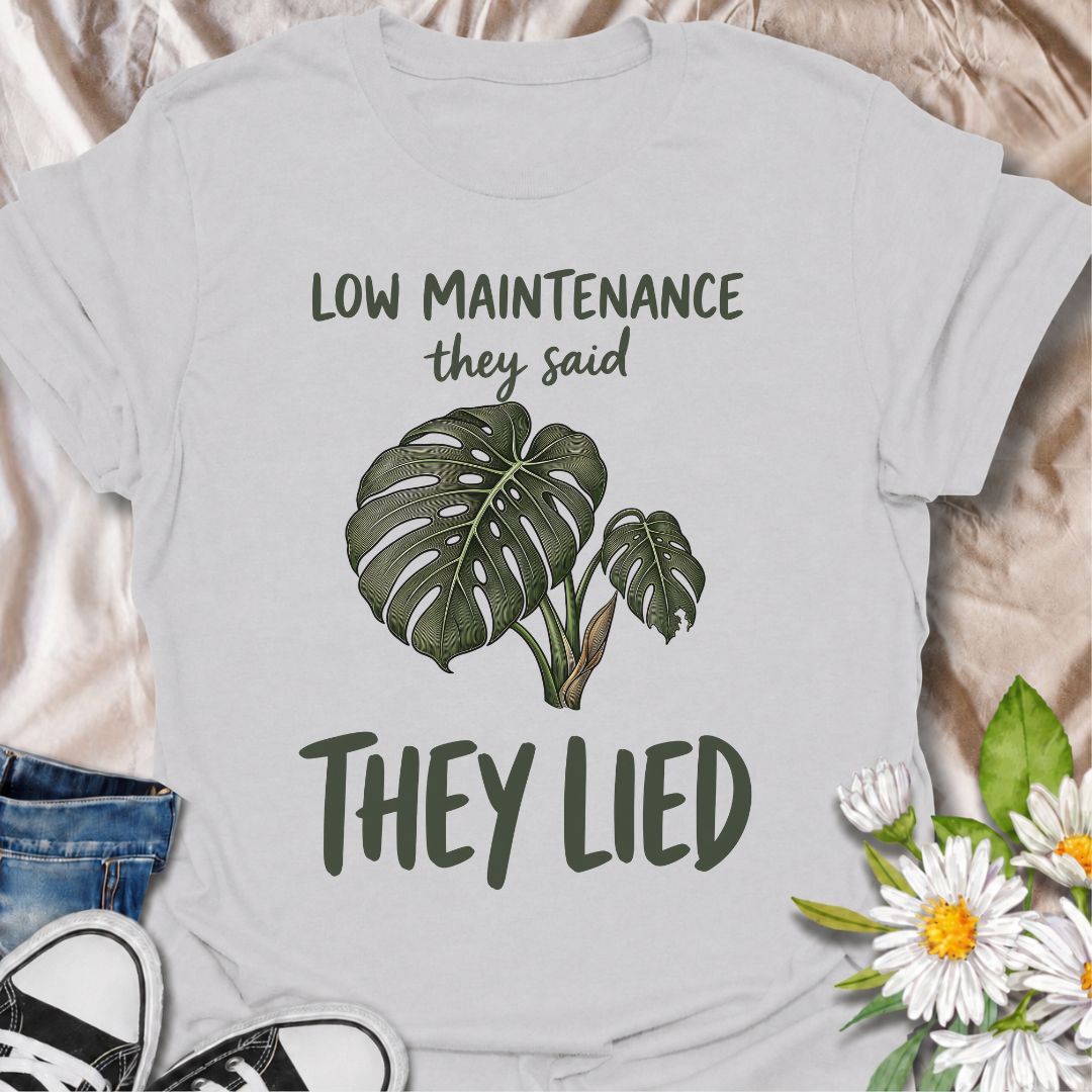 A funny plant T-shirt for anyone who was promised an easy-care houseplant and quickly discovered otherwise. The phrase “Low Maintenance, They Said. They Lied.” delivers dry, relatable humor that plant parents and monstera lovers will instantly understand. Featuring a leafy monstera illustration, the design feels simple, wearable, and clearly rooted in houseplant culture. It makes a great gift for indoor gardeners, plant collectors, and anyone who has spent far more time troubleshooting a supposedly easy pla