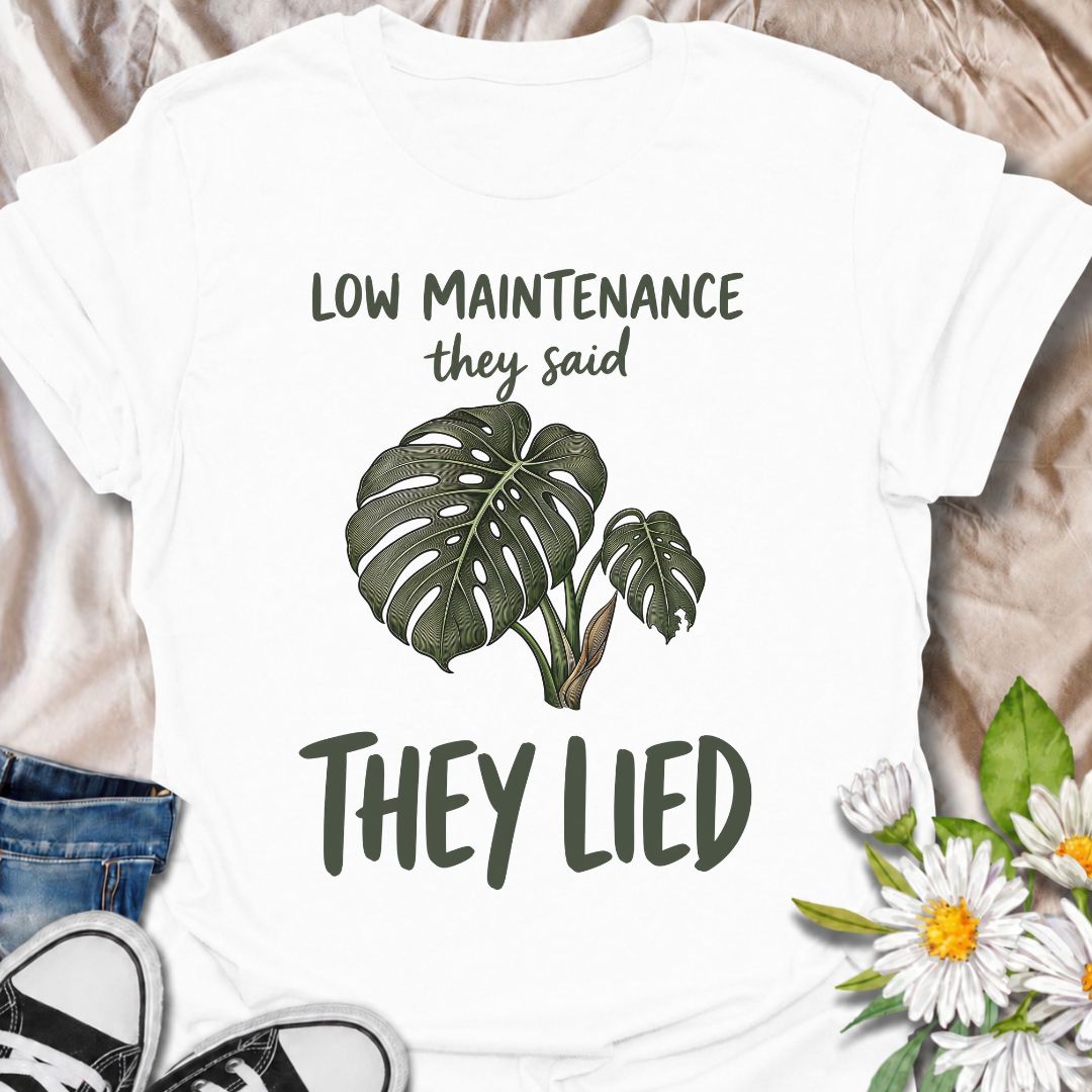 A funny plant T-shirt for anyone who was promised an easy-care houseplant and quickly discovered otherwise. The phrase “Low Maintenance, They Said. They Lied.” delivers dry, relatable humor that plant parents and monstera lovers will instantly understand. Featuring a leafy monstera illustration, the design feels simple, wearable, and clearly rooted in houseplant culture. It makes a great gift for indoor gardeners, plant collectors, and anyone who has spent far more time troubleshooting a supposedly easy pla