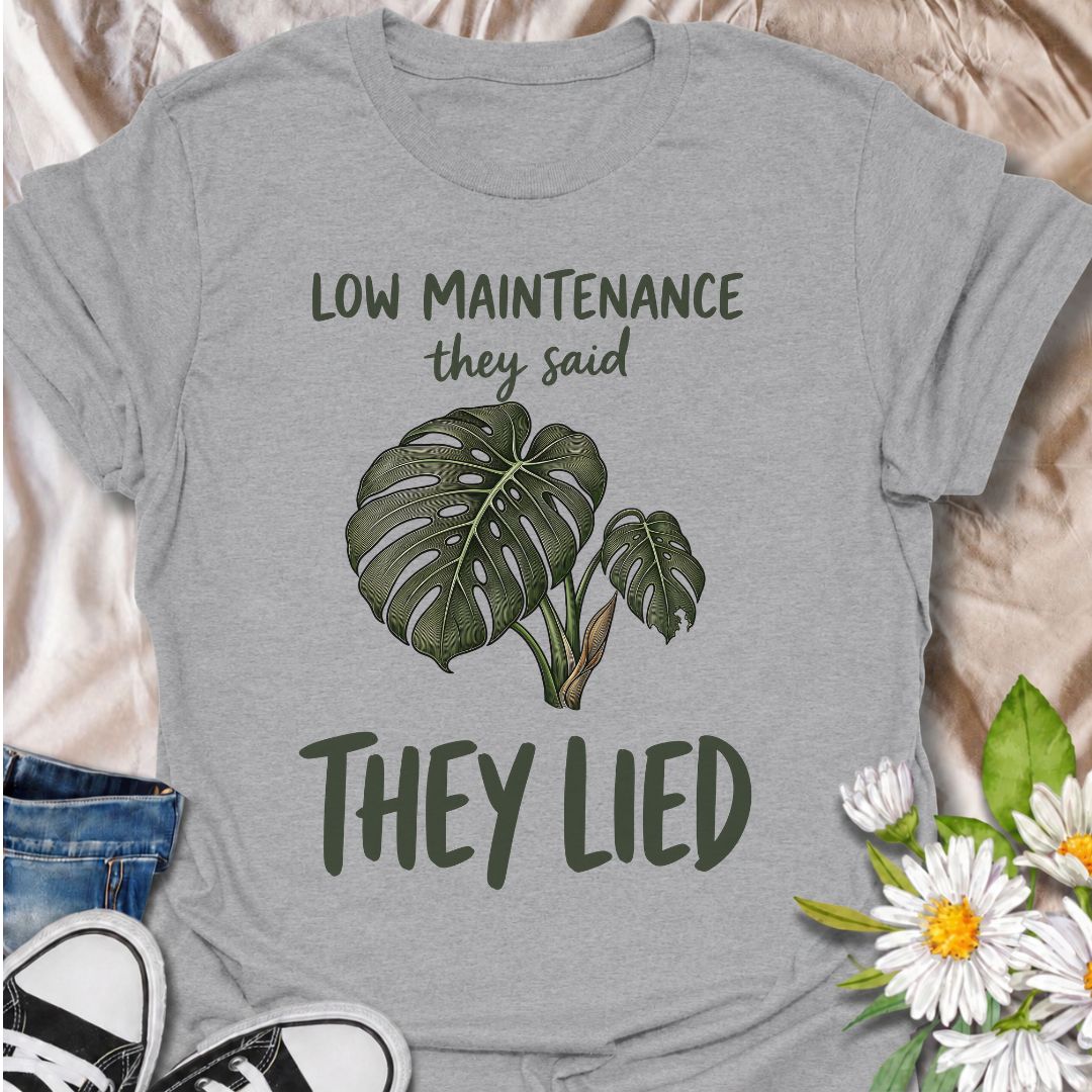 A funny plant T-shirt for anyone who was promised an easy-care houseplant and quickly discovered otherwise. The phrase “Low Maintenance, They Said. They Lied.” delivers dry, relatable humor that plant parents and monstera lovers will instantly understand. Featuring a leafy monstera illustration, the design feels simple, wearable, and clearly rooted in houseplant culture. It makes a great gift for indoor gardeners, plant collectors, and anyone who has spent far more time troubleshooting a supposedly easy pla