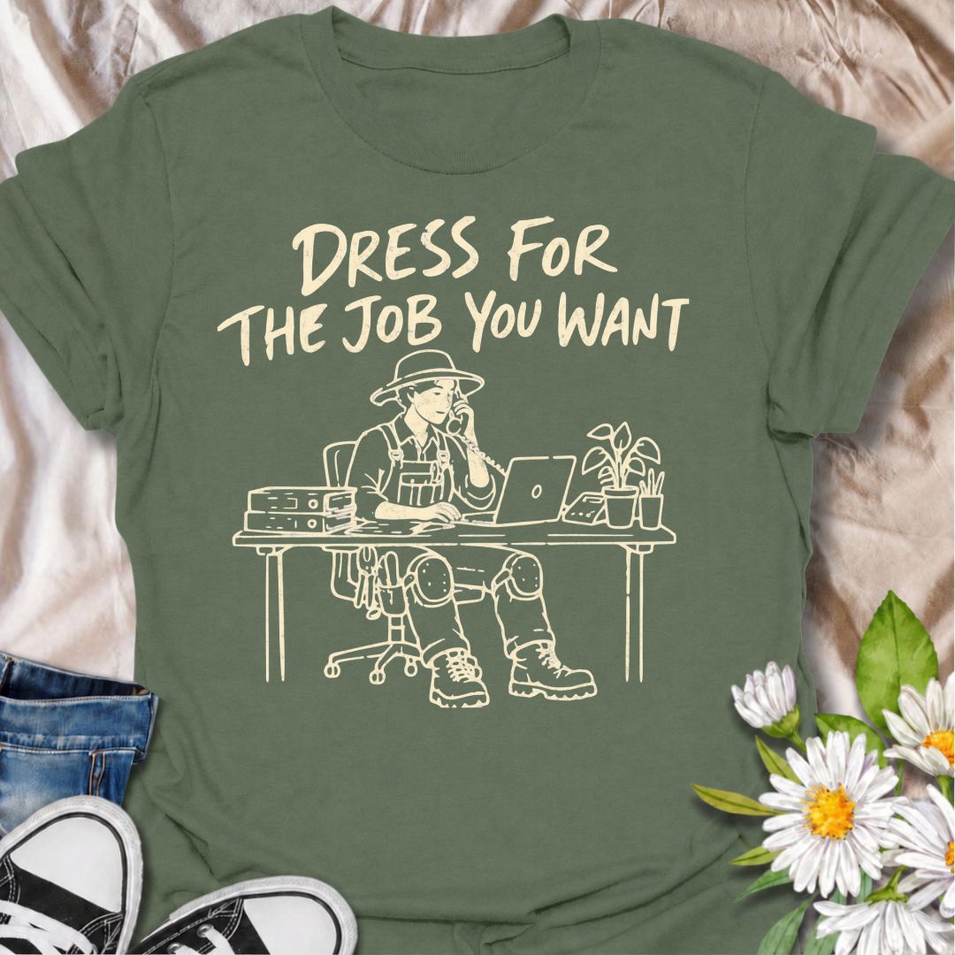 A funny gardening T-shirt for anyone who would rather be dressed for the garden than stuck behind a desk. The phrase “Dress for the Job You Want” pairs with a gardener in full work gear sitting in an office setting for a dry, absurd bit of garden humor. Featuring overalls, knee pads, work boots, tools, a laptop, and desk accessories, the design is perfect for gardeners who know exactly where they would rather be. It makes a great gift for professional gardeners, backyard growers, plant lovers, and anyone dr