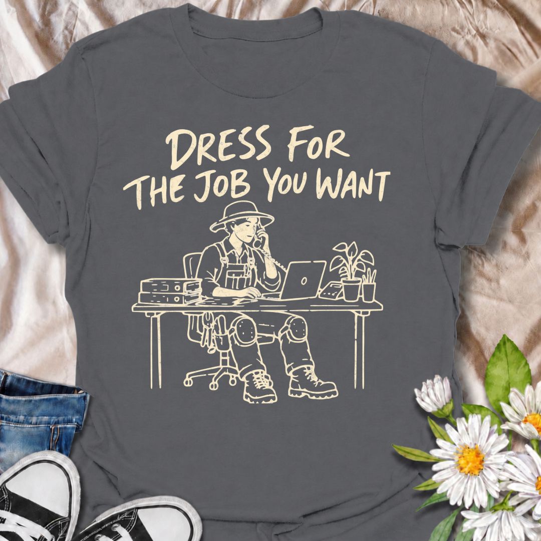 A funny gardening T-shirt for anyone who would rather be dressed for the garden than stuck behind a desk. The phrase “Dress for the Job You Want” pairs with a gardener in full work gear sitting in an office setting for a dry, absurd bit of garden humor. Featuring overalls, knee pads, work boots, tools, a laptop, and desk accessories, the design is perfect for gardeners who know exactly where they would rather be. It makes a great gift for professional gardeners, backyard growers, plant lovers, and anyone dr