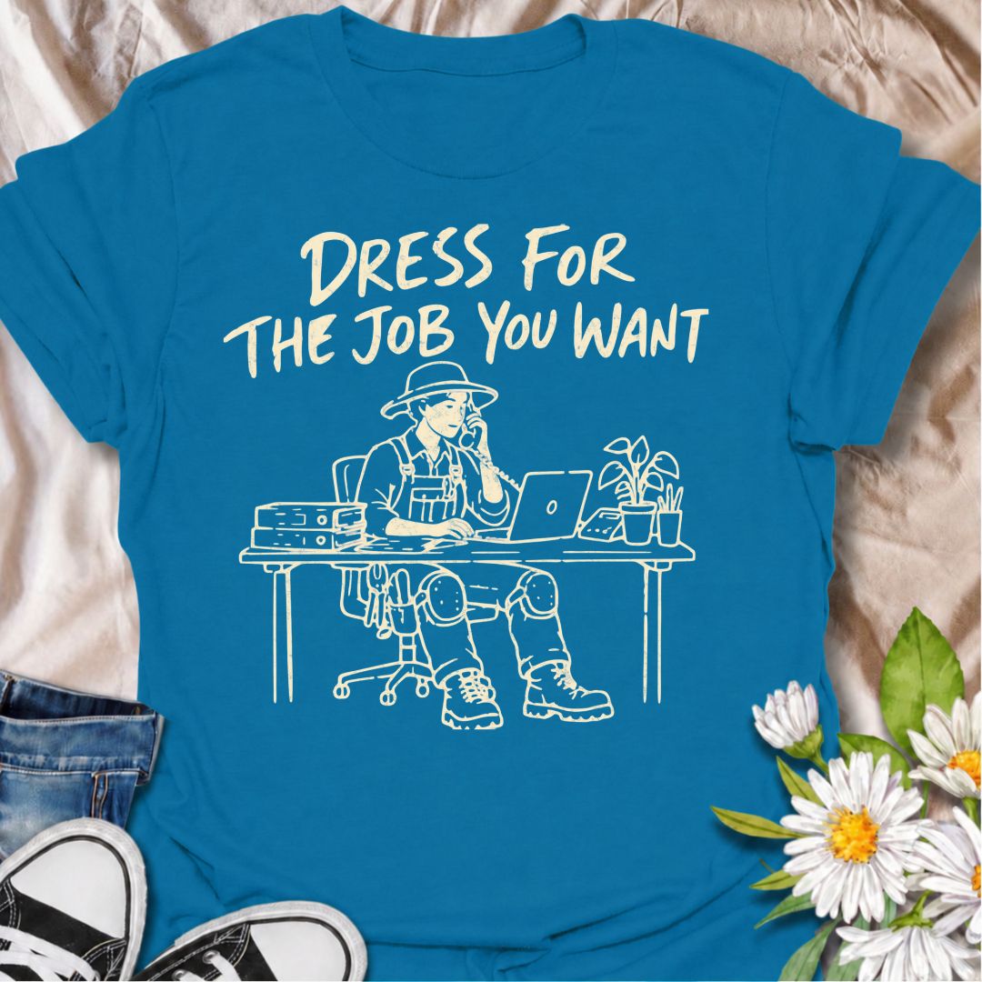 A funny gardening T-shirt for anyone who would rather be dressed for the garden than stuck behind a desk. The phrase “Dress for the Job You Want” pairs with a gardener in full work gear sitting in an office setting for a dry, absurd bit of garden humor. Featuring overalls, knee pads, work boots, tools, a laptop, and desk accessories, the design is perfect for gardeners who know exactly where they would rather be. It makes a great gift for professional gardeners, backyard growers, plant lovers, and anyone dr