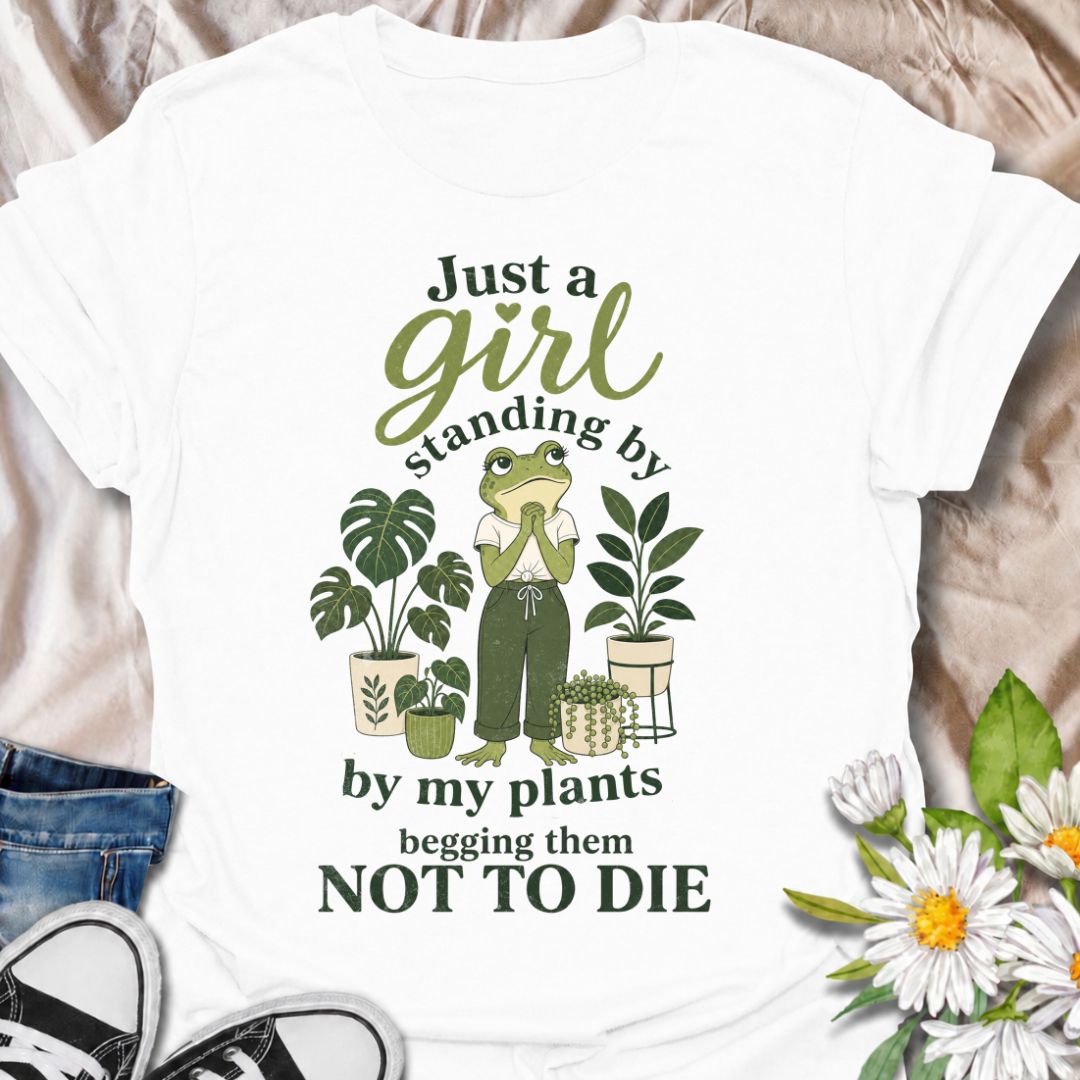 A funny plant T-shirt for anyone who spends far too much time encouraging their houseplants to stay alive. The phrase “Just a Girl Standing by My Plants Begging Them Not to Die” delivers relatable, self-deprecating humor for plant parents and indoor gardeners. Featuring a frog character surrounded by potted plants, the design feels playful, niche, and easy to wear. It makes a great gift for houseplant lovers, plant collectors, and anyone who has ever stared anxiously at a struggling leaf. Perfect for nurser