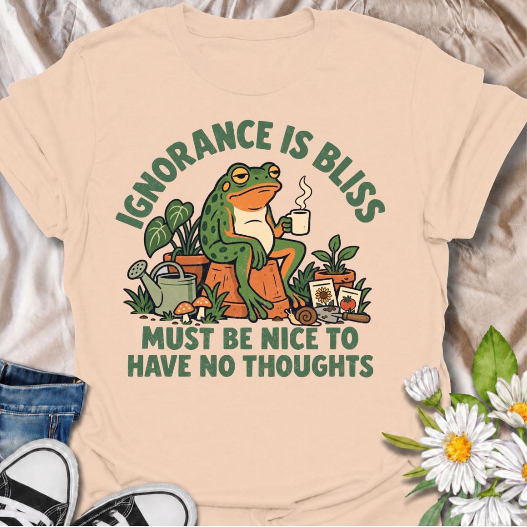 A funny gardening T-shirt for anyone who suspects life might be easier with fewer thoughts and more time around plants. The phrase “Ignorance Is Bliss — Must Be Nice to Have No Thoughts” pairs with a deadpan frog, coffee mug, potted plants, and gardening supplies for sarcastic, character-led humor. It is perfect for gardeners, plant lovers, frog fans, and anyone who enjoys a slightly dry, absurd joke. The retro illustration gives the design plenty of personality while keeping it firmly rooted in the gardeni