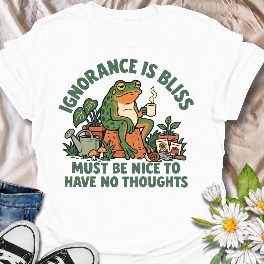 A funny gardening T-shirt for anyone who suspects life might be easier with fewer thoughts and more time around plants. The phrase “Ignorance Is Bliss — Must Be Nice to Have No Thoughts” pairs with a deadpan frog, coffee mug, potted plants, and gardening supplies for sarcastic, character-led humor. It is perfect for gardeners, plant lovers, frog fans, and anyone who enjoys a slightly dry, absurd joke. The retro illustration gives the design plenty of personality while keeping it firmly rooted in the gardeni