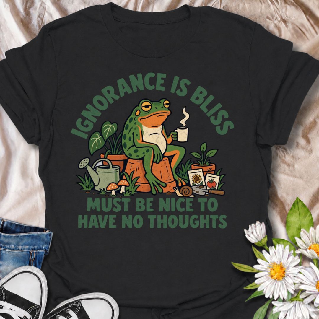 A funny gardening T-shirt for anyone who suspects life might be easier with fewer thoughts and more time around plants. The phrase “Ignorance Is Bliss — Must Be Nice to Have No Thoughts” pairs with a deadpan frog, coffee mug, potted plants, and gardening supplies for sarcastic, character-led humor. It is perfect for gardeners, plant lovers, frog fans, and anyone who enjoys a slightly dry, absurd joke. The retro illustration gives the design plenty of personality while keeping it firmly rooted in the gardeni