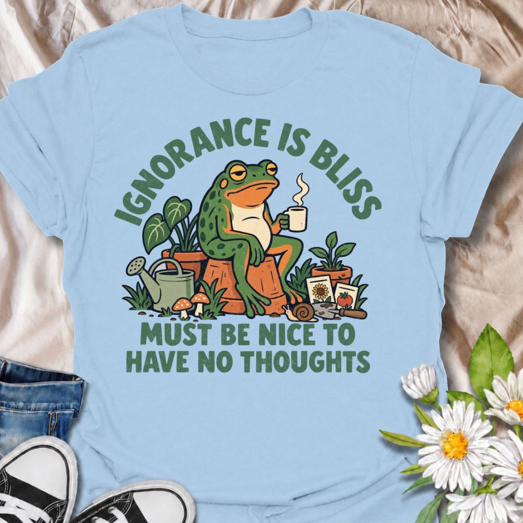 A funny gardening T-shirt for anyone who suspects life might be easier with fewer thoughts and more time around plants. The phrase “Ignorance Is Bliss — Must Be Nice to Have No Thoughts” pairs with a deadpan frog, coffee mug, potted plants, and gardening supplies for sarcastic, character-led humor. It is perfect for gardeners, plant lovers, frog fans, and anyone who enjoys a slightly dry, absurd joke. The retro illustration gives the design plenty of personality while keeping it firmly rooted in the garden