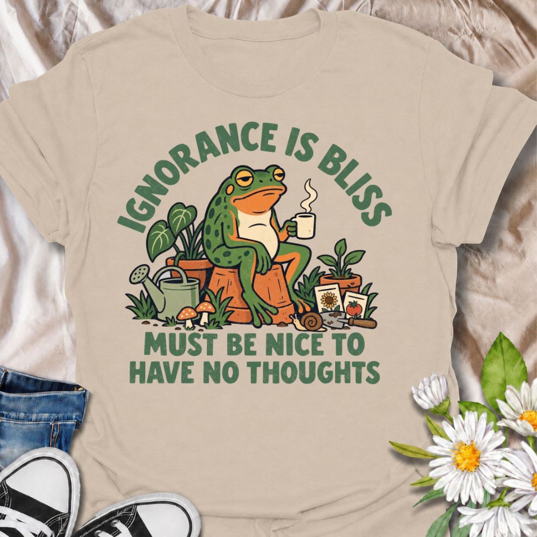 A funny gardening T-shirt for anyone who suspects life might be easier with fewer thoughts and more time around plants. The phrase “Ignorance Is Bliss — Must Be Nice to Have No Thoughts” pairs with a deadpan frog, coffee mug, potted plants, and gardening supplies for sarcastic, character-led humor. It is perfect for gardeners, plant lovers, frog fans, and anyone who enjoys a slightly dry, absurd joke. The retro illustration gives the design plenty of personality while keeping it firmly rooted in the gardeni