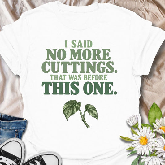 A funny propagation T-shirt for anyone who swore they were done taking cuttings until the next irresistible stem appeared. The phrase “I Said No More Cuttings. That Was Before This One.” captures the familiar logic of plant lovers who can always justify one more propagation. Featuring a simple leafy cutting beneath bold retro typography, the design stays clean, readable, and easy to wear. It makes a great gift for houseplant collectors, pothos lovers, propagation fans, and anyone with jars of cuttings takin