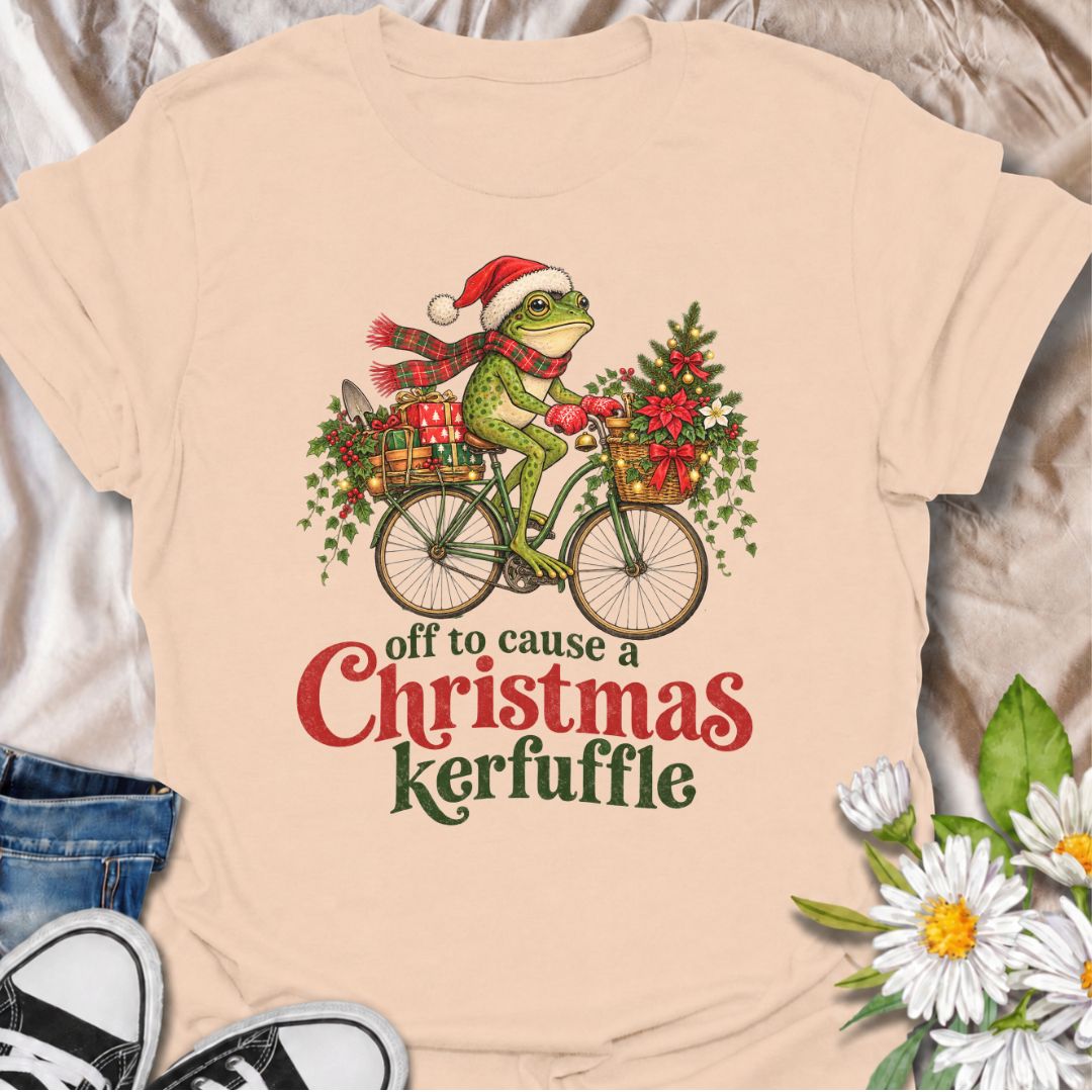 A funny Christmas gardening T-shirt featuring a determined frog cycling off to cause a little festive trouble. The phrase “Off to Cause a Christmas Kerfuffle” combines Botanic Weave’s deadpan frog humor with holly, gifts, garden tools, and plenty of Christmas cheer. It is perfect for gardeners, frog lovers, plant people, and anyone who prefers their holiday shirts funny rather than overly sweet. The detailed vintage-style illustration gives it a festive storybook feel while keeping the joke front and center