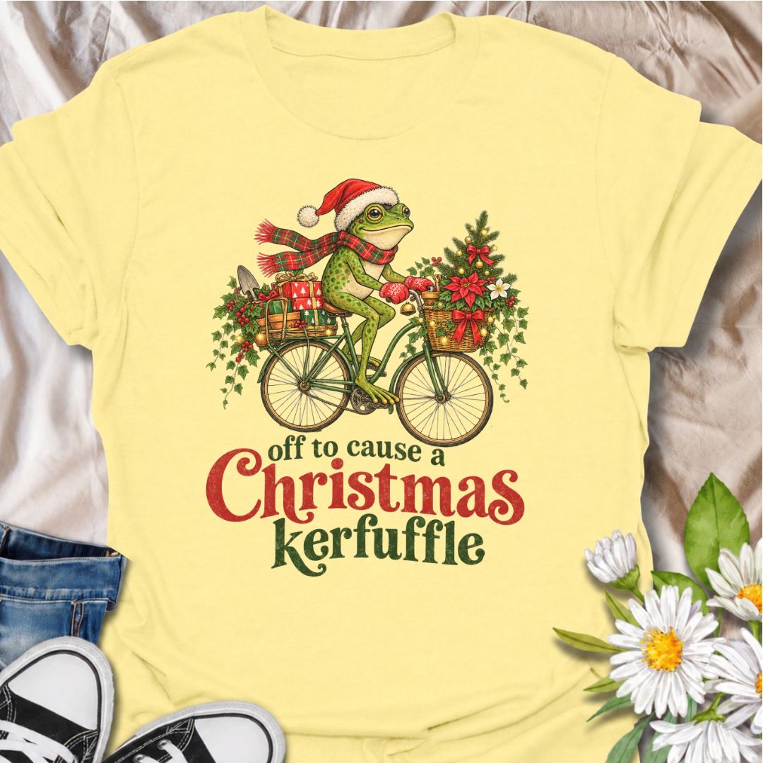 A funny Christmas gardening T-shirt featuring a determined frog cycling off to cause a little festive trouble. The phrase “Off to Cause a Christmas Kerfuffle” combines Botanic Weave’s deadpan frog humor with holly, gifts, garden tools, and plenty of Christmas cheer. It is perfect for gardeners, frog lovers, plant people, and anyone who prefers their holiday shirts funny rather than overly sweet. The detailed vintage-style illustration gives it a festive storybook feel while keeping the joke front and center