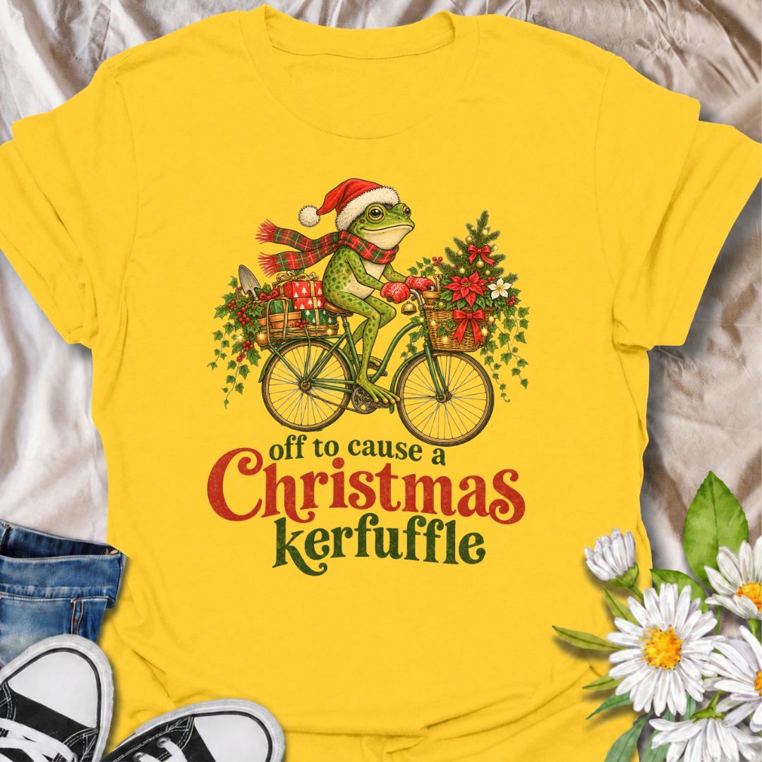 A funny Christmas gardening T-shirt featuring a determined frog cycling off to cause a little festive trouble. The phrase “Off to Cause a Christmas Kerfuffle” combines Botanic Weave’s deadpan frog humor with holly, gifts, garden tools, and plenty of Christmas cheer. It is perfect for gardeners, frog lovers, plant people, and anyone who prefers their holiday shirts funny rather than overly sweet. The detailed vintage-style illustration gives it a festive storybook feel while keeping the joke front and center