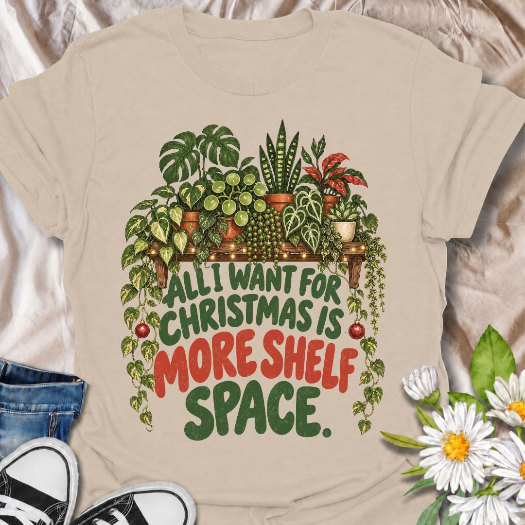 A funny Christmas plant T-shirt for anyone whose real holiday wish is simply more room for houseplants. The phrase “All I Want for Christmas Is More Shelf Space” pairs with a lush plant-filled shelf, trailing vines, fairy lights, and festive ornaments for a design made especially for serious plant collectors. It is perfect for plant parents, houseplant lovers, indoor gardeners, and anyone whose shelves are already overflowing with greenery. The Christmas details make it festive without losing the everyday p