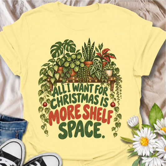 A funny Christmas plant T-shirt for anyone whose real holiday wish is simply more room for houseplants. The phrase “All I Want for Christmas Is More Shelf Space” pairs with a lush plant-filled shelf, trailing vines, fairy lights, and festive ornaments for a design made especially for serious plant collectors. It is perfect for plant parents, houseplant lovers, indoor gardeners, and anyone whose shelves are already overflowing with greenery. The Christmas details make it festive without losing the everyday p