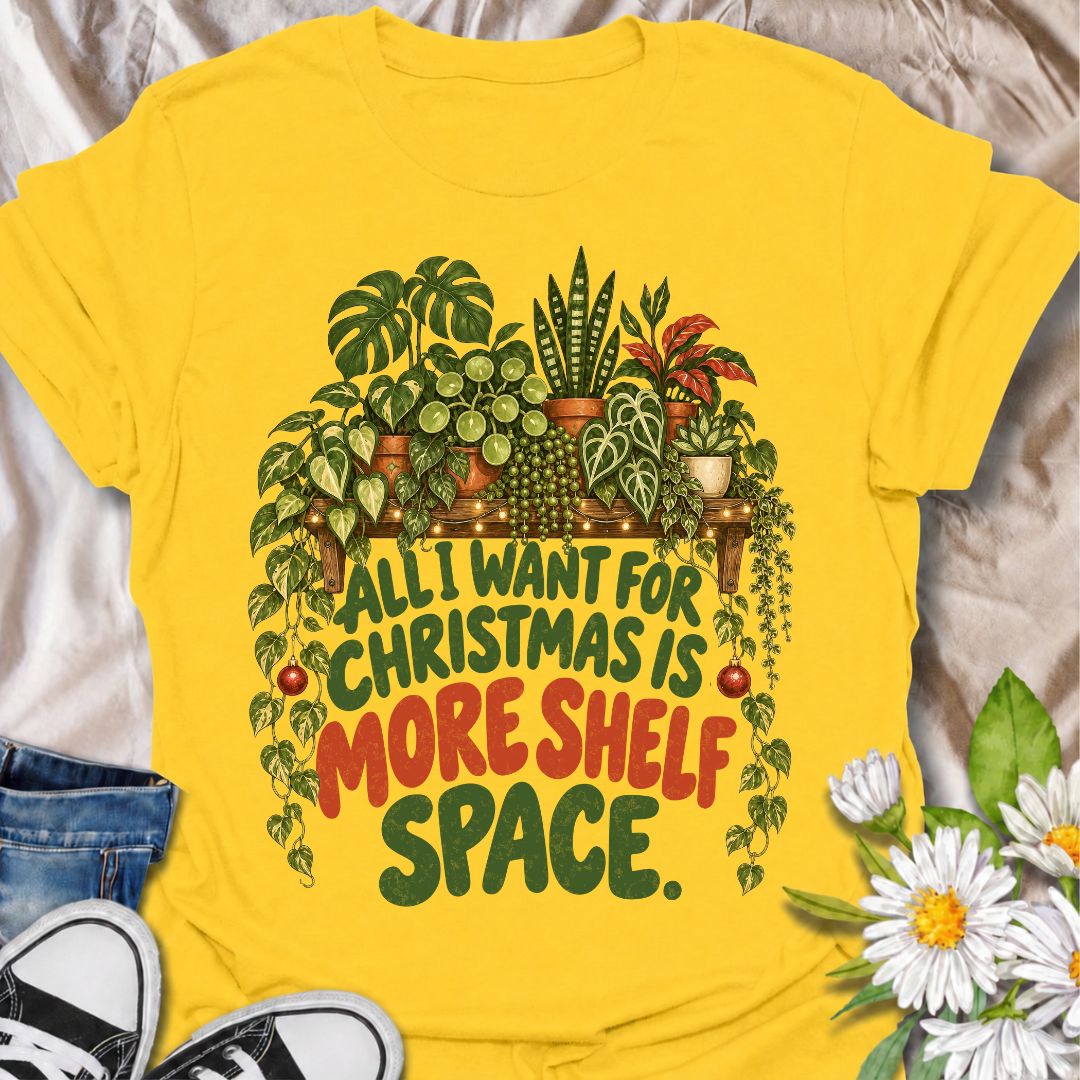 A funny Christmas plant T-shirt for anyone whose real holiday wish is simply more room for houseplants. The phrase “All I Want for Christmas Is More Shelf Space” pairs with a lush plant-filled shelf, trailing vines, fairy lights, and festive ornaments for a design made especially for serious plant collectors. It is perfect for plant parents, houseplant lovers, indoor gardeners, and anyone whose shelves are already overflowing with greenery. The Christmas details make it festive without losing the everyday p