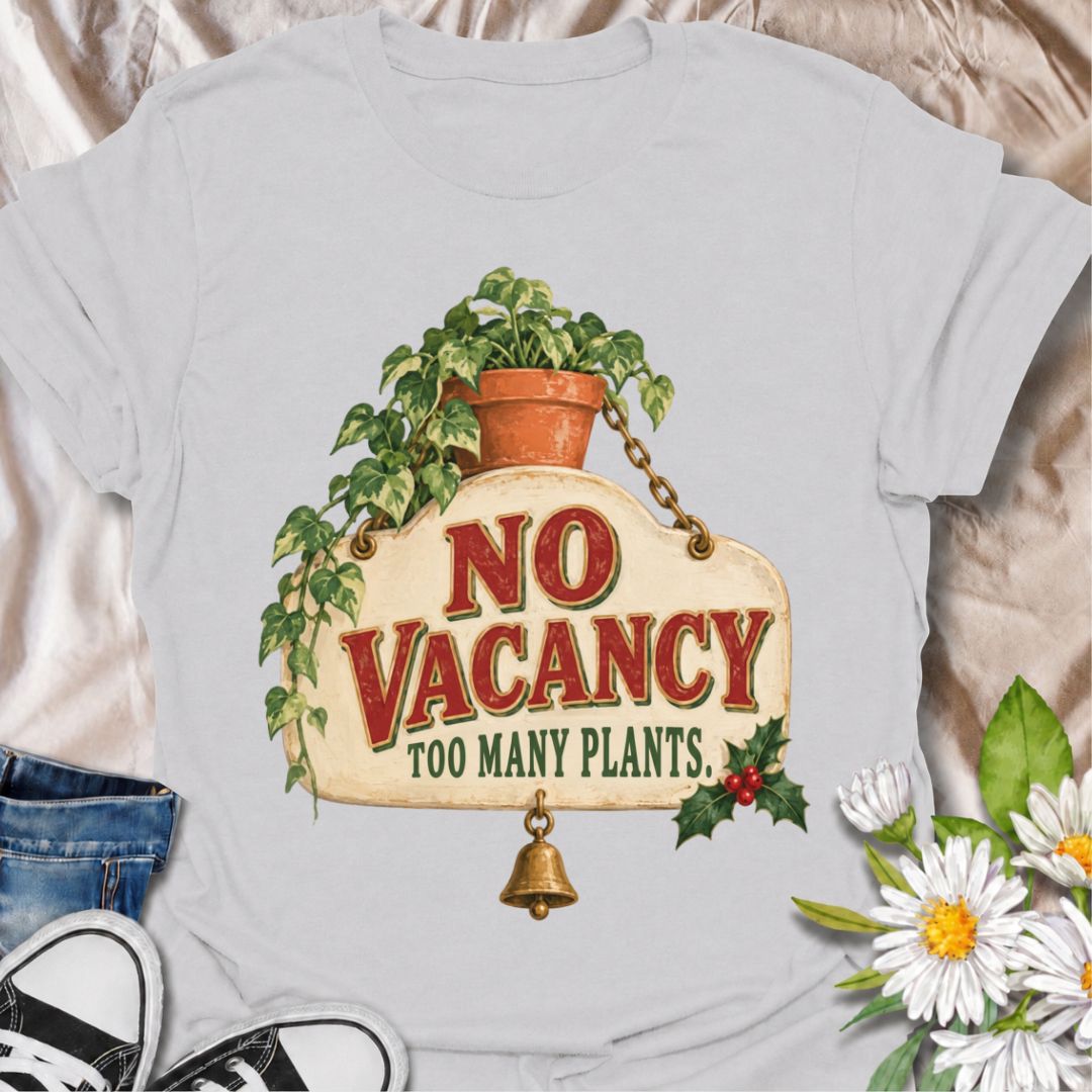 A funny Christmas plant T-shirt for anyone whose home has officially run out of room for more greenery. The phrase “No Vacancy — Too Many Plants” pairs with a vintage hanging sign, trailing houseplant, holly, and a little bell for a festive plant-lover design. It is perfect for houseplant collectors, plant parents, indoor gardeners, and anyone whose shelves and windowsills are already full. The retro sign styling gives it a cozy holiday feel while keeping the joke easy to read. A great Christmas gift for pl