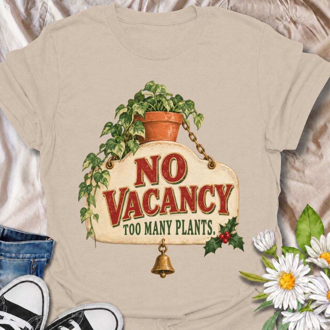 A funny Christmas plant T-shirt for anyone whose home has officially run out of room for more greenery. The phrase “No Vacancy — Too Many Plants” pairs with a vintage hanging sign, trailing houseplant, holly, and a little bell for a festive plant-lover design. It is perfect for houseplant collectors, plant parents, indoor gardeners, and anyone whose shelves and windowsills are already full. The retro sign styling gives it a cozy holiday feel while keeping the joke easy to read. A great Christmas gift for pl