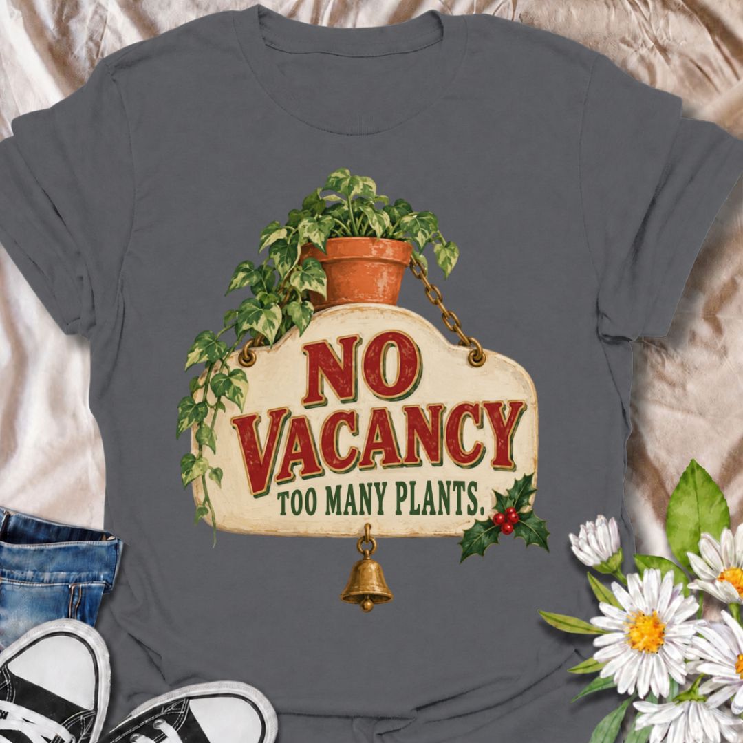 A funny Christmas plant T-shirt for anyone whose home has officially run out of room for more greenery. The phrase “No Vacancy — Too Many Plants” pairs with a vintage hanging sign, trailing houseplant, holly, and a little bell for a festive plant-lover design. It is perfect for houseplant collectors, plant parents, indoor gardeners, and anyone whose shelves and windowsills are already full. The retro sign styling gives it a cozy holiday feel while keeping the joke easy to read. A great Christmas gift for pl