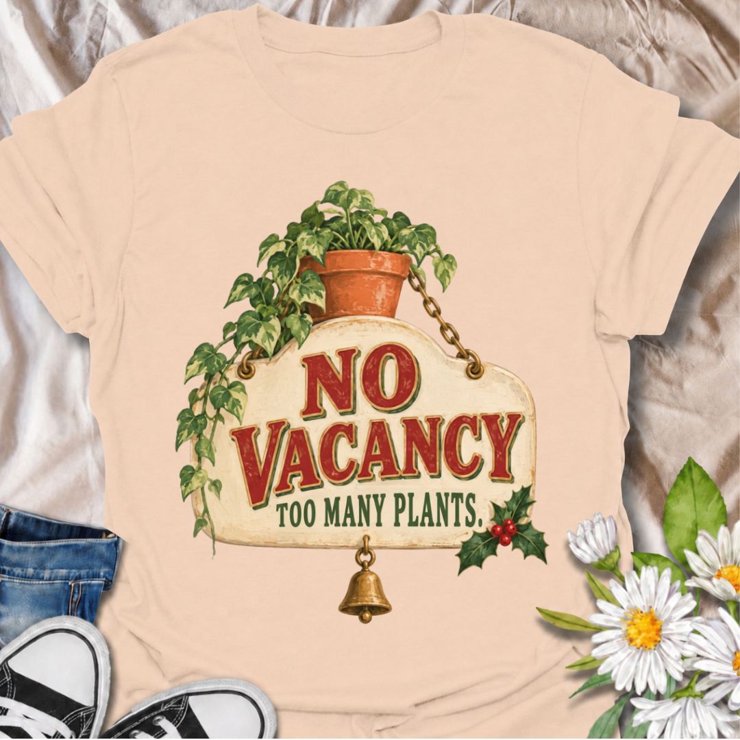 A funny Christmas plant T-shirt for anyone whose home has officially run out of room for more greenery. The phrase “No Vacancy — Too Many Plants” pairs with a vintage hanging sign, trailing houseplant, holly, and a little bell for a festive plant-lover design. It is perfect for houseplant collectors, plant parents, indoor gardeners, and anyone whose shelves and windowsills are already full. The retro sign styling gives it a cozy holiday feel while keeping the joke easy to read. A great Christmas gift for pl
