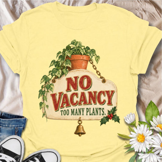 A funny Christmas plant T-shirt for anyone whose home has officially run out of room for more greenery. The phrase “No Vacancy — Too Many Plants” pairs with a vintage hanging sign, trailing houseplant, holly, and a little bell for a festive plant-lover design. It is perfect for houseplant collectors, plant parents, indoor gardeners, and anyone whose shelves and windowsills are already full. The retro sign styling gives it a cozy holiday feel while keeping the joke easy to read. A great Christmas gift for pl